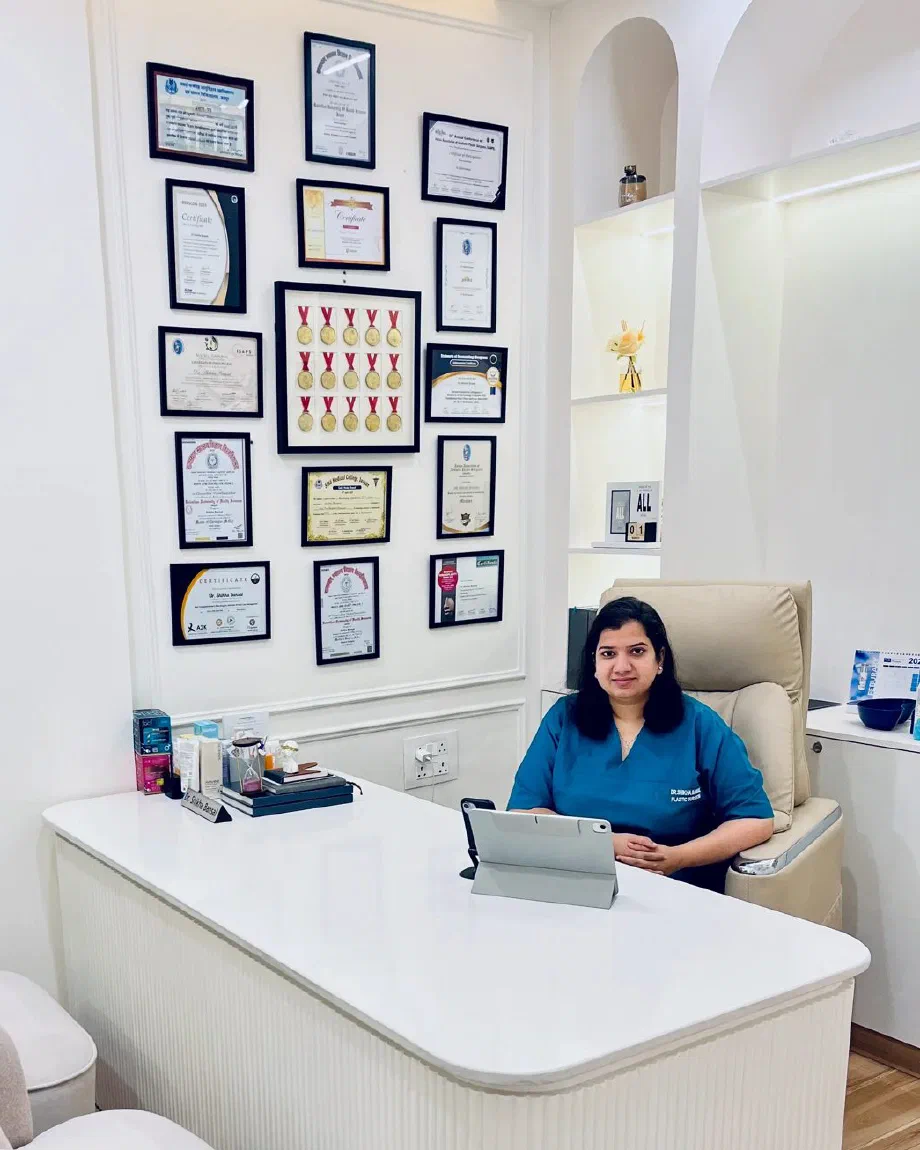 Dr. Shikha Bansal at her desk in the white consultation room at Dr. Shikha Aesthetics